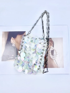Close-up of iridescent sequins and silver chain strap on a designer shoulder bag