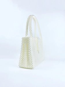 Detailed view of the 3D rectangular structure of a white handcrafted woven pearl handbag