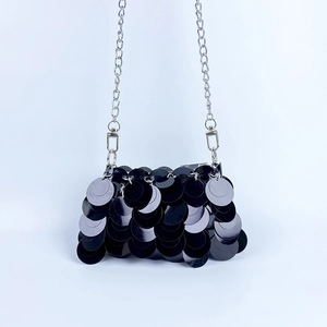 Gros plan des paillettes noires brillantes et de la chaîne argentée du sac de soirée