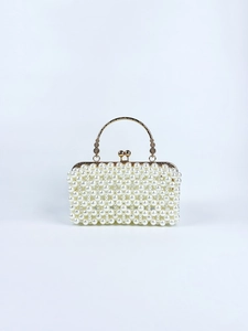 Detail of elegant handmade pearl evening bag with gold woven handle and metal clasp