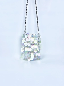 Close-up of holographic large sequins on a shiny chain crossbody bag with iridescent finish