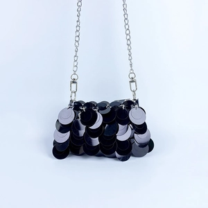 Détail d'un sac de soirée à paillettes noires avec chaîne en argent et texture brillante