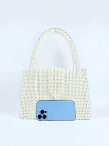 Detailed view of woven white pearl handbag next to a smartphone for size reference