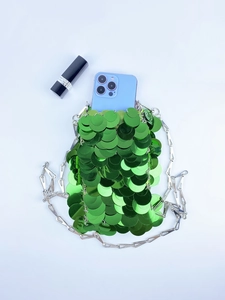 Detail view of green sequin handbag with fish-scale texture and silver metal chain