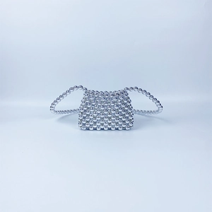 Detail of a silver beaded mini bag featuring a handmade metallic spherical woven texture