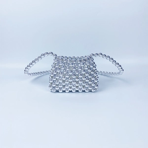 Macro detail of silver beaded mini crossbody bag featuring handmade metallic bead texture
