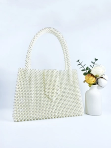 Detail of hand-woven white pearl beaded tote bag with elegant arched handle and floral decor