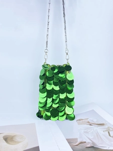 Detail of green sequin crossbody bag featuring metallic discs and silver chain strap