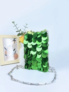 Sparkly green sequin crossbody bag with silver chain strap on elegant background