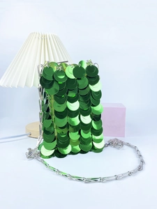 Close-up of green sequin handbag with silver chain strap and shiny metallic finish