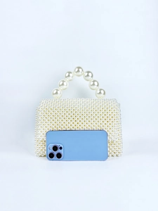Detail view of handmade pearl beaded handbag with large top handle and mobile phone for scale
