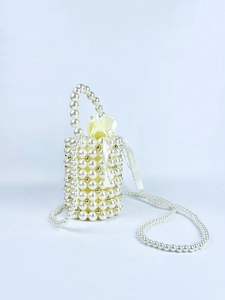 Detail of handcrafted pearl cylinder bag with gold bead accents and satin drawstring lining