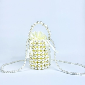 Detailed close-up of handmade pearl bucket bag with satin lining and metal bead accents