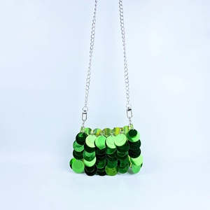 Détail d'un sac de soirée à paillettes vertes avec bandoulière chaîne en métal argenté