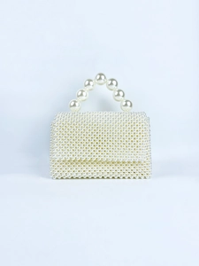 Macro detail of dense white pearl woven texture and large beaded handle on evening bag