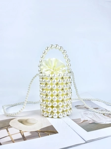 Detail of handmade pearl bucket bag with gold accents and drawstring satin liner