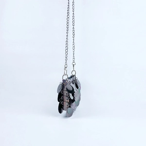 Détails des paillettes gris foncé et de la chaîne argentée sur un mini sac à bandoulière