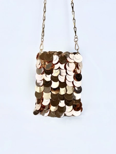 Detailed view of shimmering gold sequin mesh and metallic chain strap on a small bag