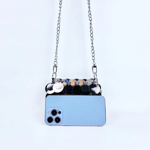 Détail du sac de soirée à paillettes avec chaîne métallique comparé à un smartphone
