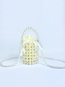Detail of handmade pearl bucket bag with gold accents and yellow satin drawstring liner