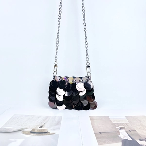 Détail des grandes paillettes et de la bandoulière chaîne en argent du sac de soirée
