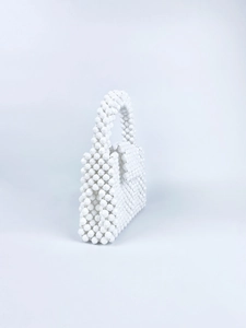Macro shot of white handmade beaded handbag with faceted beads and flap closure