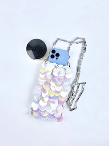 Close-up of a white sequin mini crossbody bag with a silver chain and smartphone inside