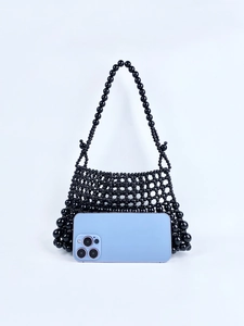 Détail de la texture perlée noire et comparaison de taille avec un smartphone de sac