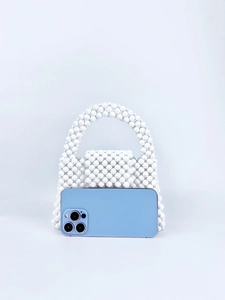 Miniature white beaded handbag shown next to a smartphone for a precise size comparison