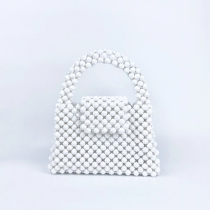 Detailed view of the handcrafted white beaded texture and trapezoid structure of the handbag