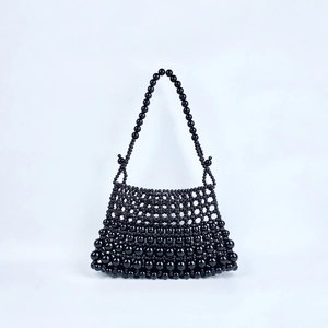 Détail d'un sac à bandoulière en perles noires fait main avec texture tissée et billes polies