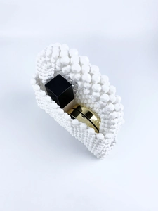Detailed interior view of a white handmade beaded handbag with lipstick and compact