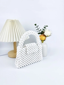 Detailed view of handmade white beaded handbag with intricate woven texture and bead structure