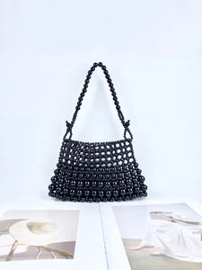 Sac à main artisanal en perles noires avec un design trapézoïdal sur un magazine