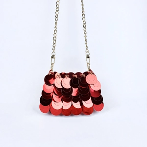 Détail des paillettes rouges vives et de la bandoulière dorée de ce sac de soirée chic