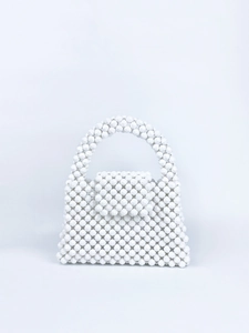 Detailed close-up of white handcrafted beaded handbag with smooth glossy texture