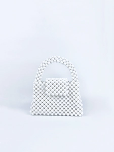 Detailed view of handcrafted white beaded handbag featuring faceted pearls and flap closure