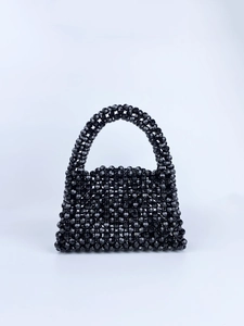Detail of the trapezoidal black beaded handbag with faceted glossy surface textures