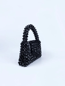 Detailed view of the handcrafted black faceted beadwork and woven texture on a handbag