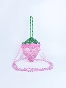 Dettaglio della borsa a fragola di perline rosa con trama chiara e foglia verde