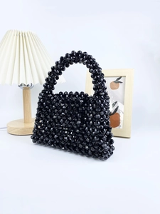 Close-up of handmade black beaded handbag featuring faceted acrylic beads and woven texture