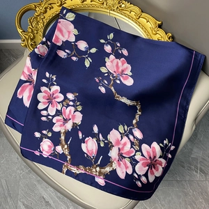 Carré de soie satinée bleu marine avec imprimés de magnolia rose sur une chaise rétro