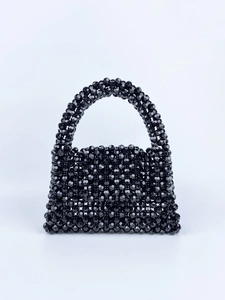 Detail of hand-woven black beaded handbag showing glossy faceted beads and craftsmanship