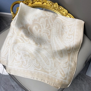 Champagne paisley satin silk square scarf with lace edge on a grey leather chair