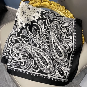 Satin square scarf with black and white paisley and polka dot prints on a chair