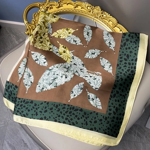Satin silk scarf with leopard print border and leaf pattern on a vintage chair