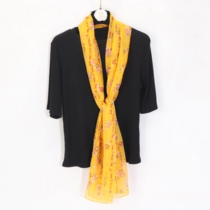 Detail of a floral chiffon scarf draped on a black ribbed short sleeve top on a hanger