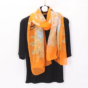 Détail d'une écharpe en mousseline orange avec des motifs de pivoines sur un support