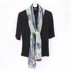 Detail of tropical leaf print chiffon scarf paired with a black ribbed knit top