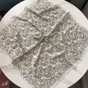Détail d'un foulard en soie vintage aux motifs cachemire sur une table en marbre blanc